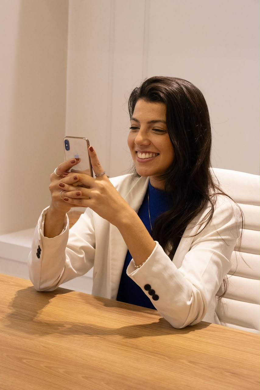 Juliana de Oliveira atendendo uma mensagem em seu consultório